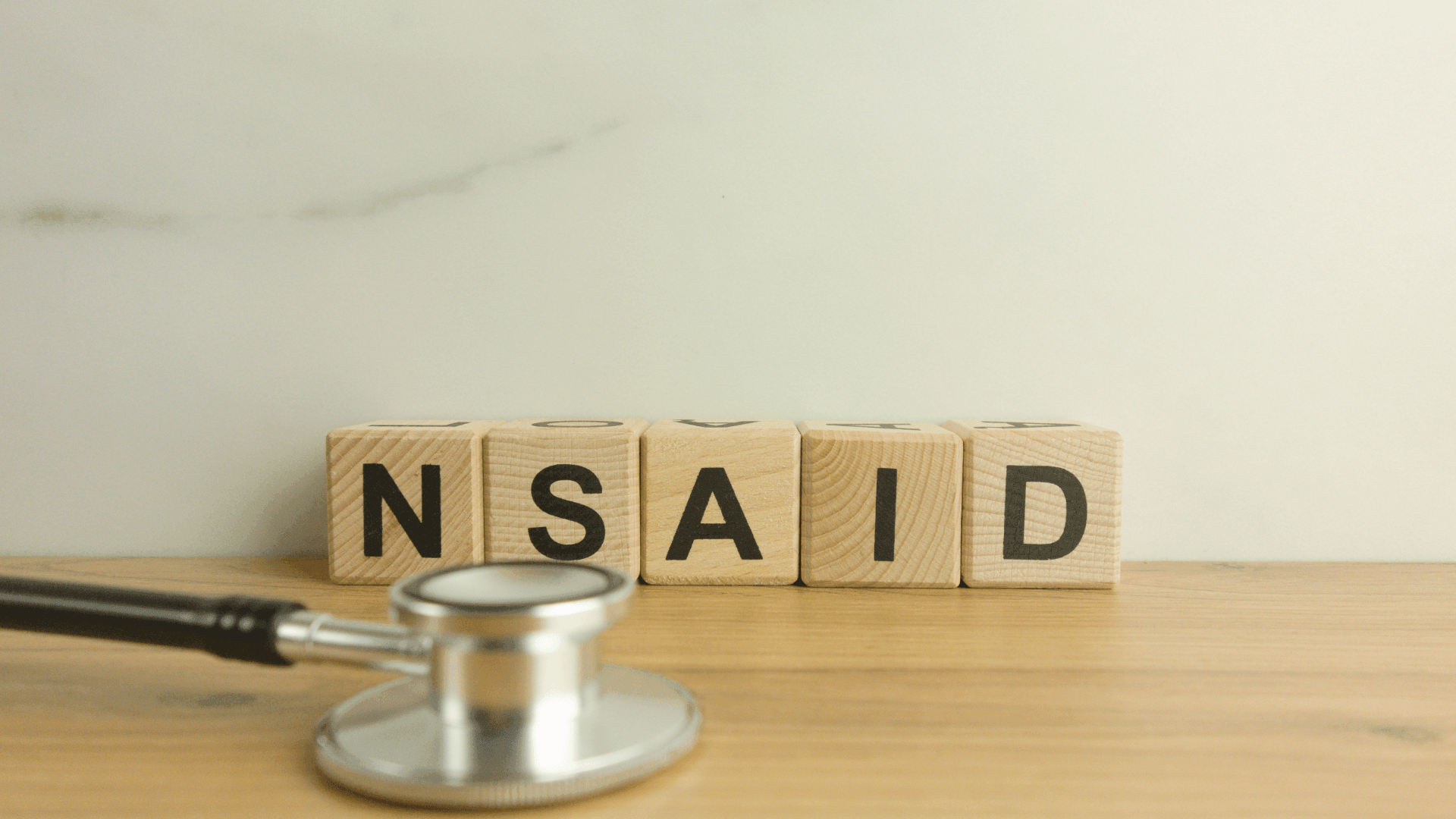 Wooden blocks with words NSAID and a stethoscope on table