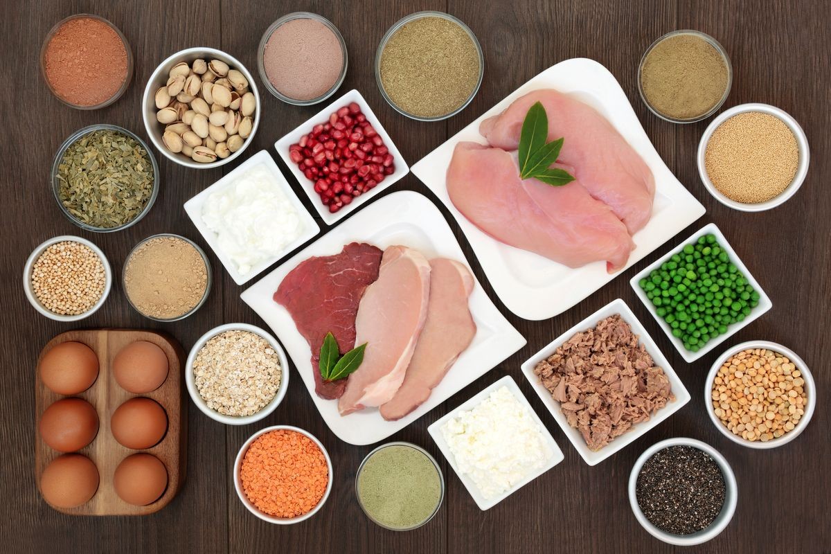 Body building health food with high protein lean chicken, steak and pork meat, dairy, supplement powders, legumes, nuts, seeds, cereals, grain, ginkgo tea, vegetables and fruit. Top view on oak wood.