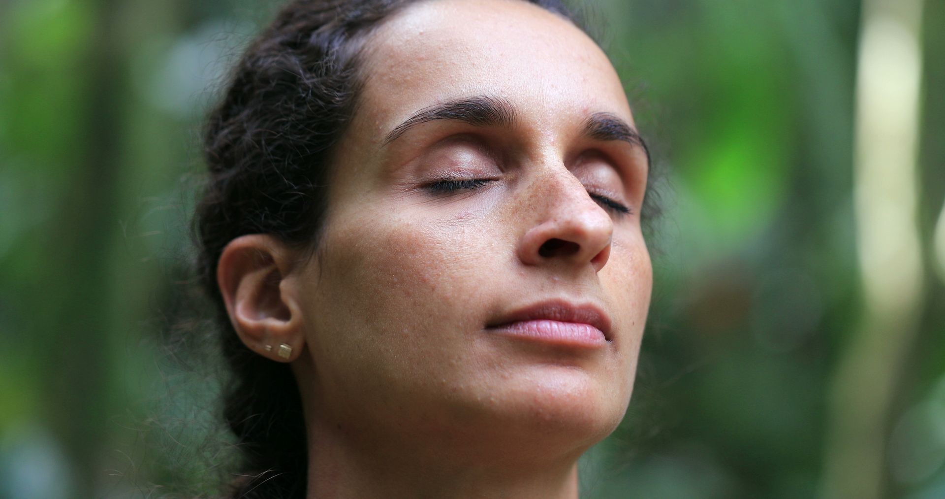 Woman meditating outdoors, taking a deep breath with eyes closed